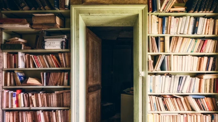 Rows of books on a wooden library shelf, representing Arkansas libraries now enforcing the state's book restriction law